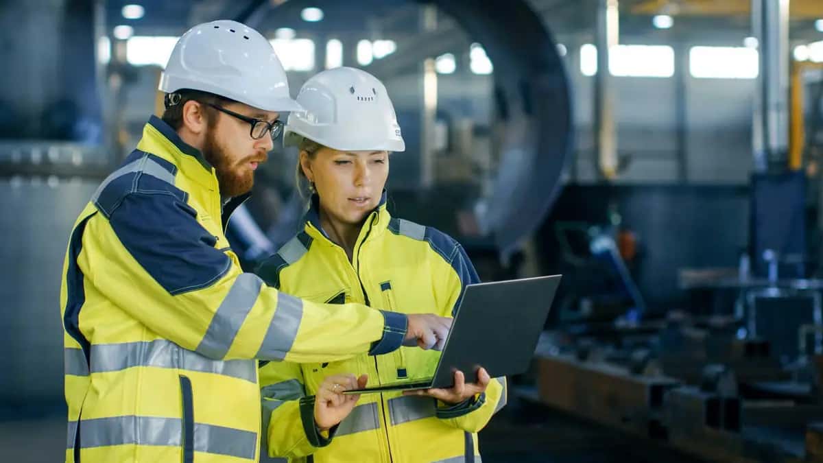 Two engineers reviewing data on a tablet in an industrial hall