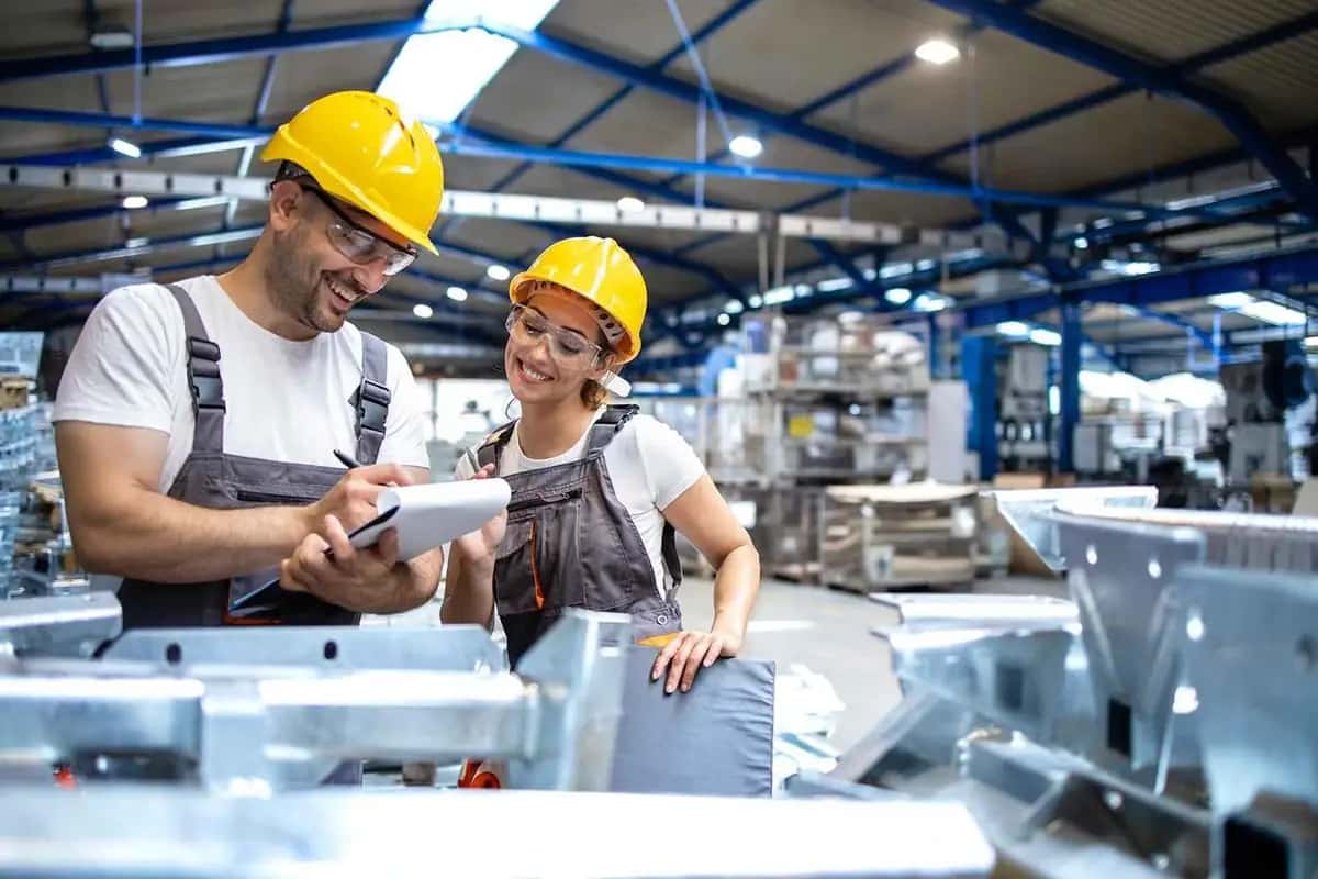 Two factory workers reviewing notes together on the shop floor