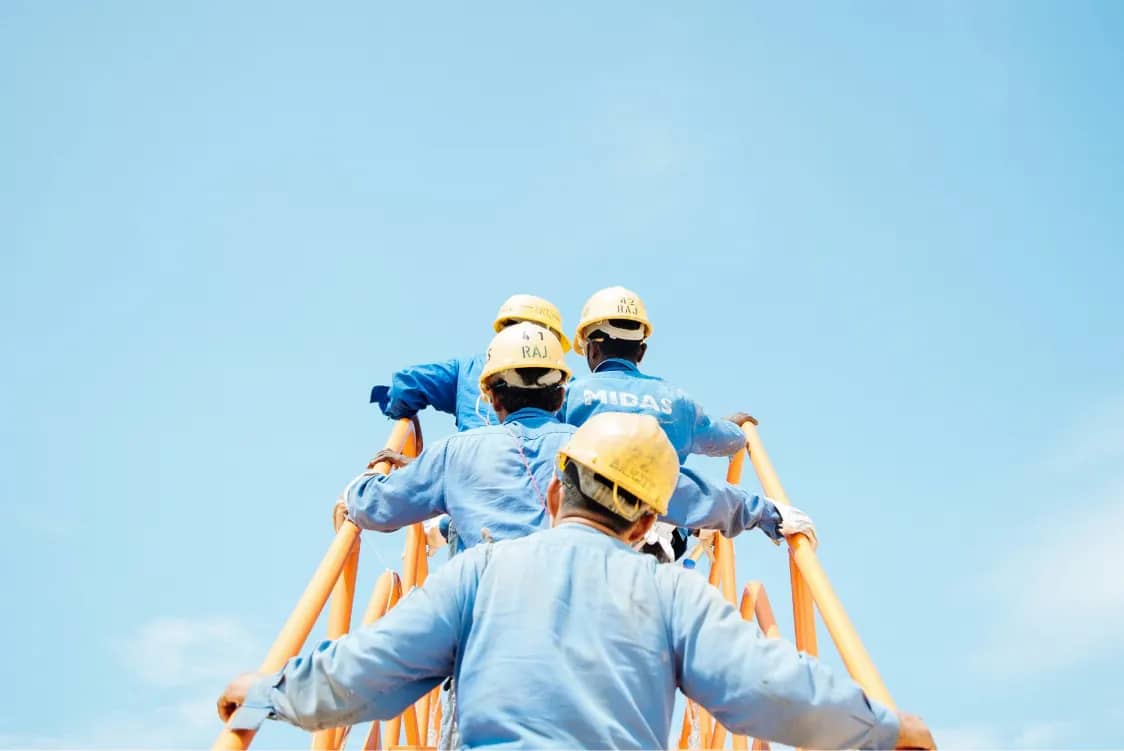Workers in blue uniforms climbing a yellow industrial structure