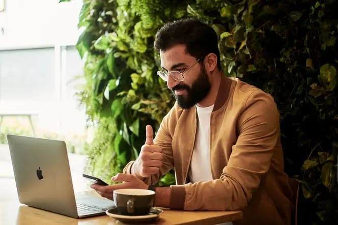 Man giving a thumbs up while working on a laptop