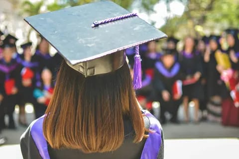 Graduate looking toward a crowd of fellow graduates