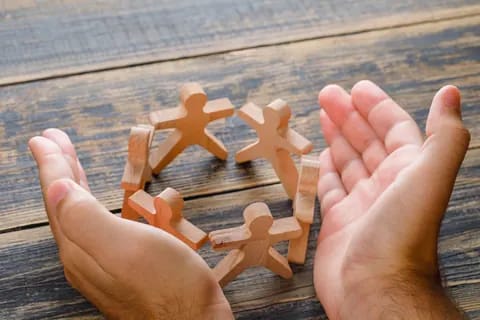 Hands cupped around wooden figures in a circle