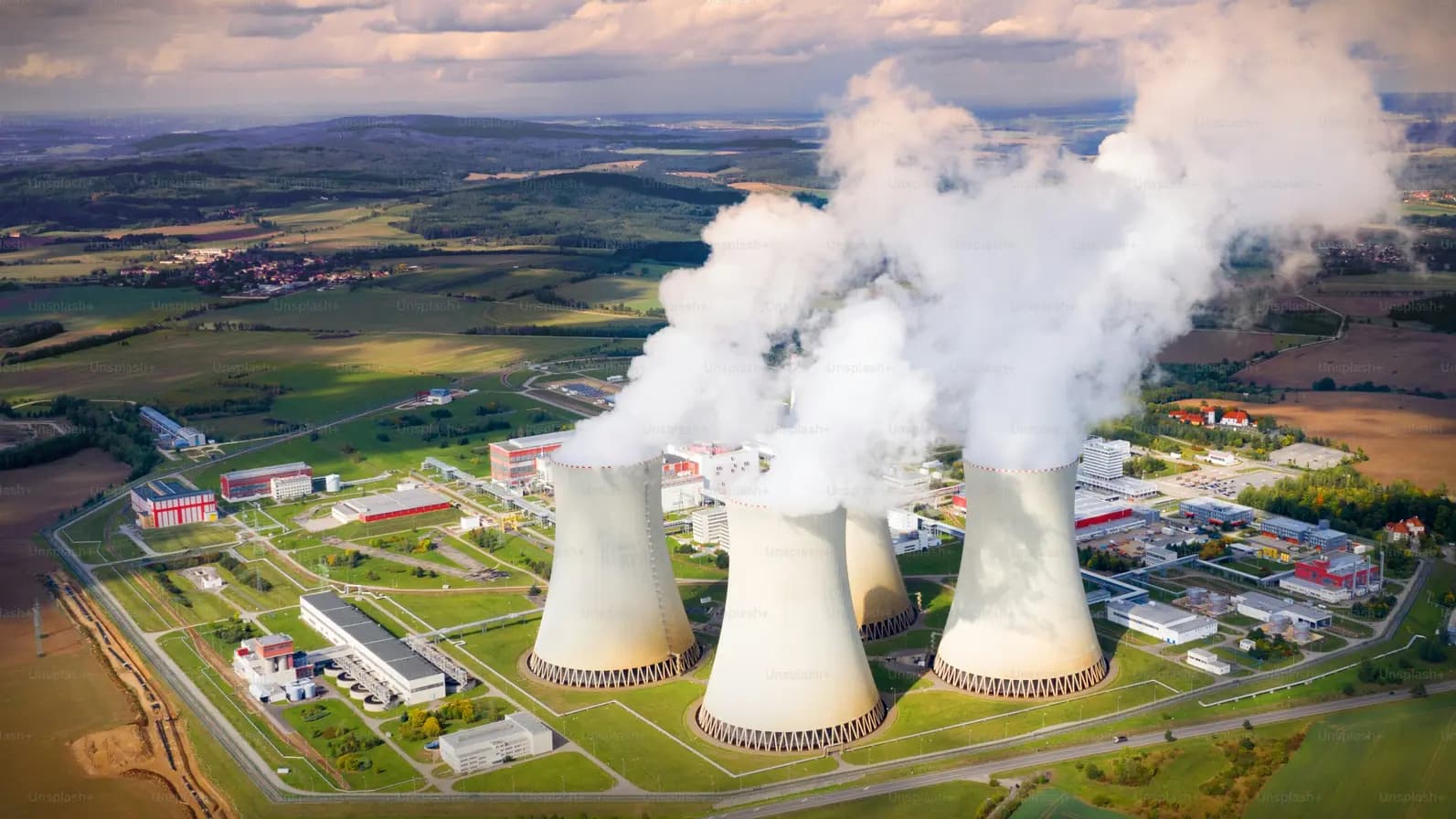 Industrial cooling towers releasing steam against a blue sky
